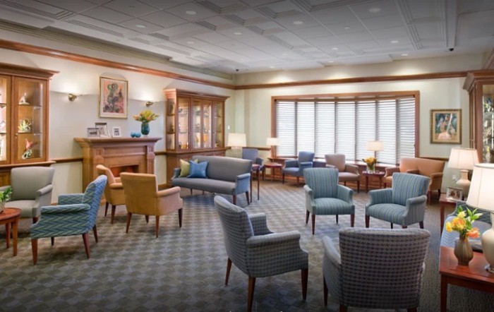 A comfortable waiting area with sofas, chairs, and tables arranged on a carpeted floor.