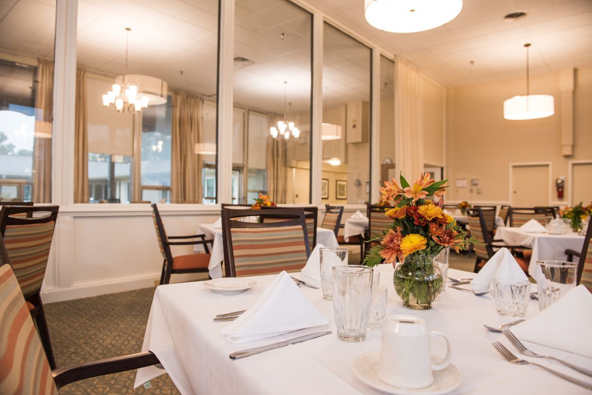 A beautifully set dining room with elegant decor, featuring a table adorned with a floral centerpiece and surrounded by comfortable chairs.