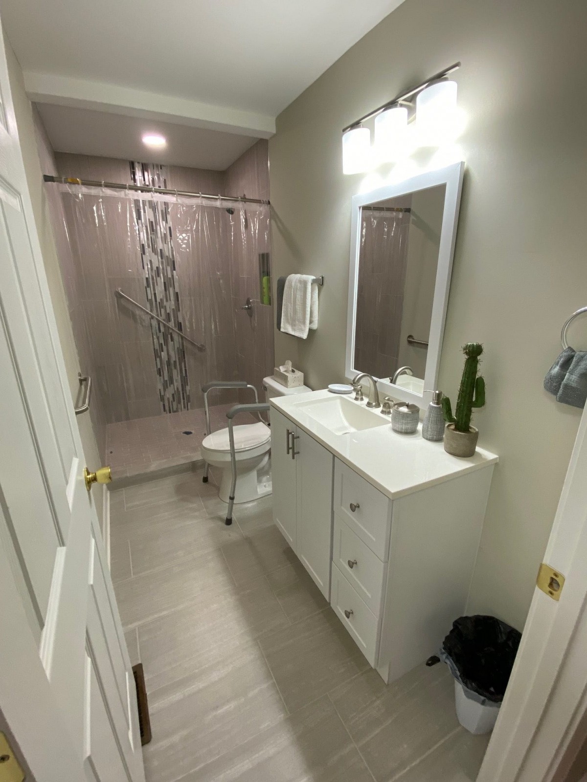A modern bathroom with a vanity, mirror, and shower area.