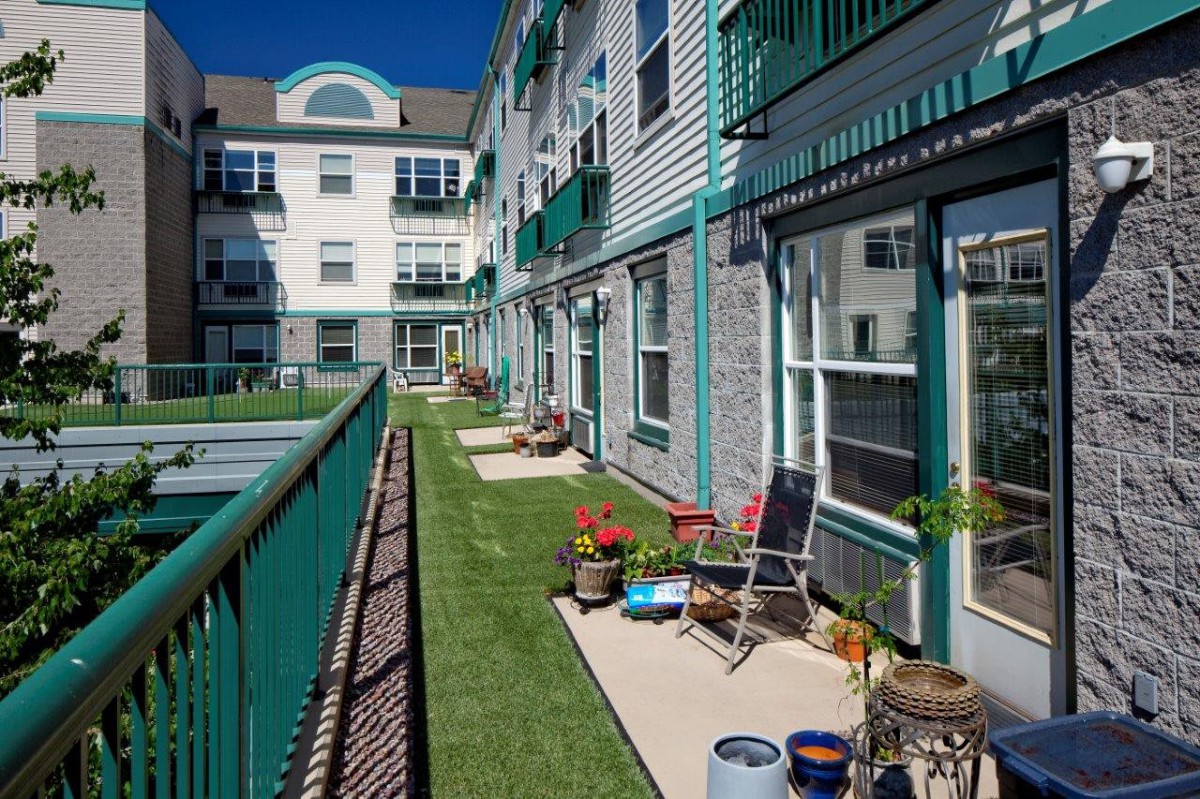 A residential building with balconies and patios adorned with outdoor seating and potted plants.