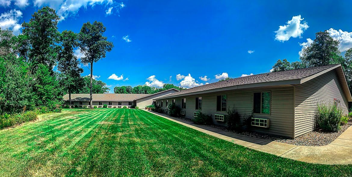 A scenic view of a building with a well-maintained lawn under a clear blue sky.