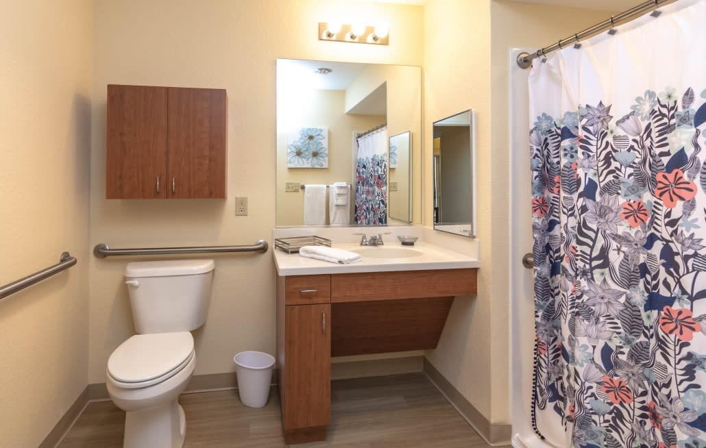 A modern bathroom with a sink, mirror, toilet, and shower curtain.