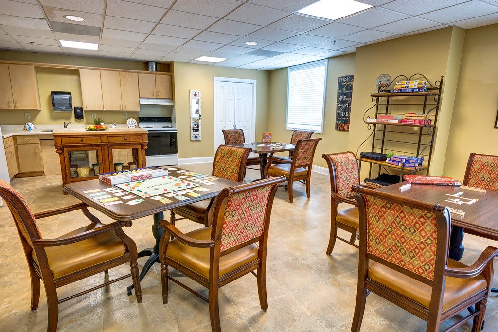 A well-lit indoor dining area with a kitchen and tables set up for playing board games.