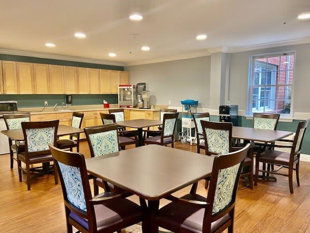A cozy dining area with multiple tables and a kitchen in the background.