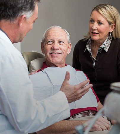 A doctor consulting with an elderly patient and a companion.