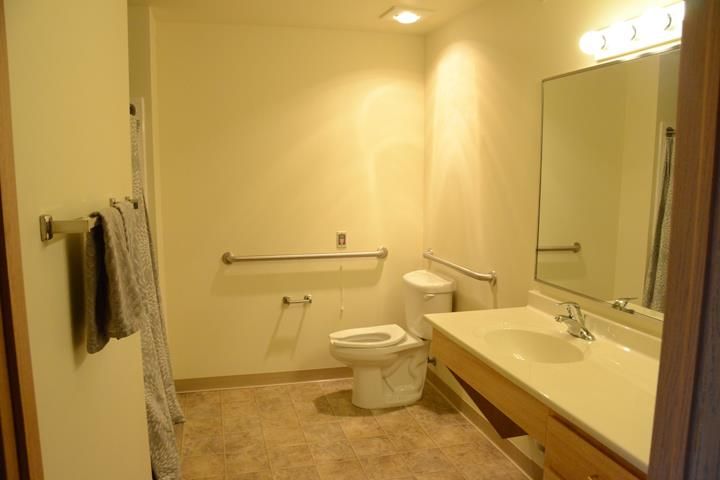 Accessible bathroom with a sink, toilet, and handrail.