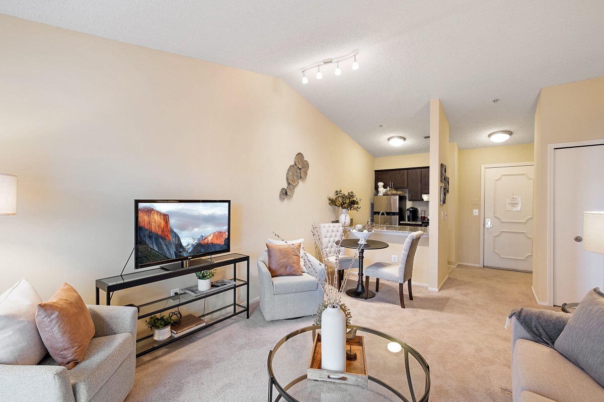 A modern and cozy living room with a TV, seating area, and a small dining space.