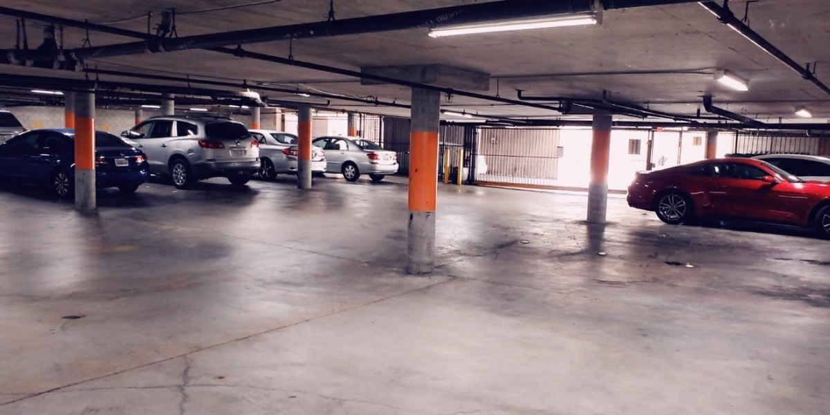 An indoor parking garage with several parked cars and empty spaces.