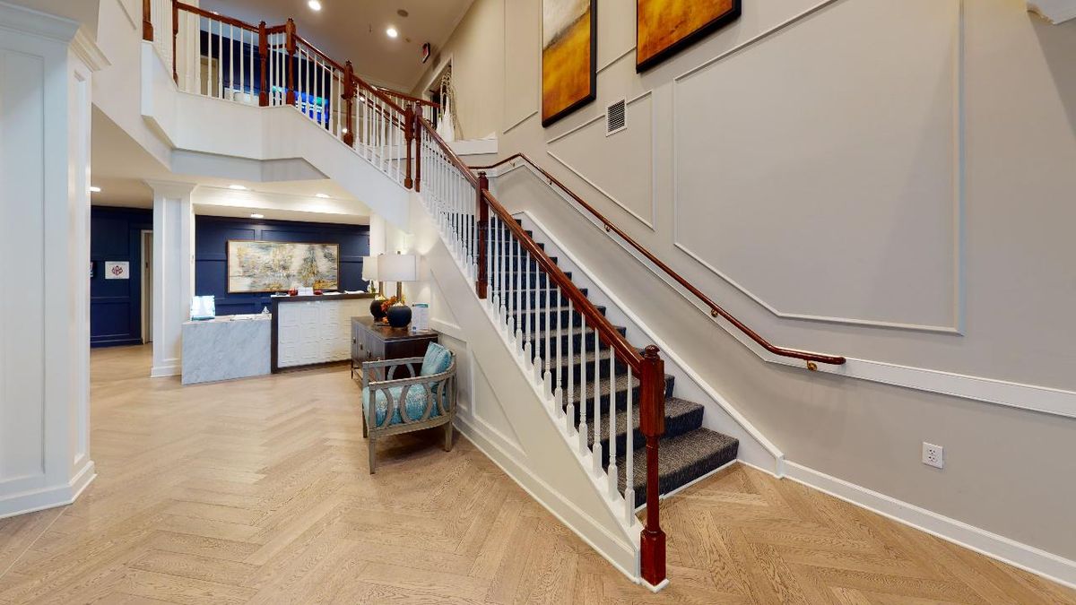 A spacious interior lobby featuring a staircase with wooden railings and modern artwork on the walls.
