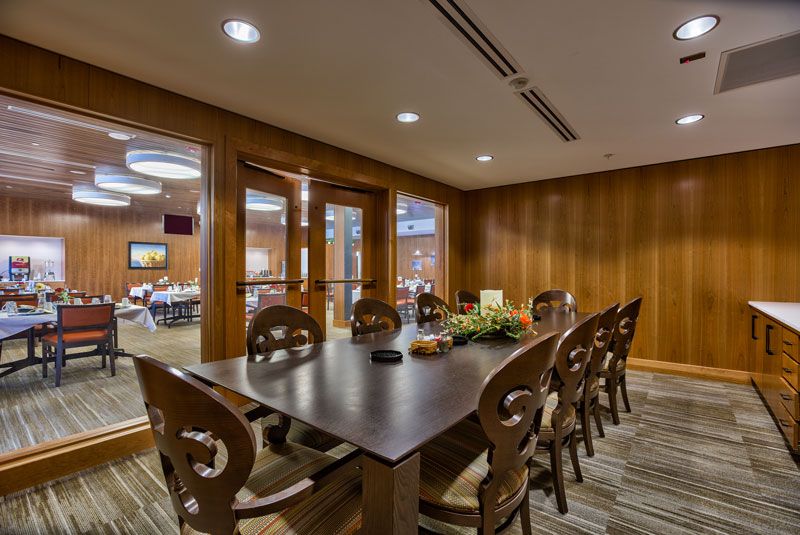 A cozy conference room with a large wooden table and chairs, suitable for meetings or dining.