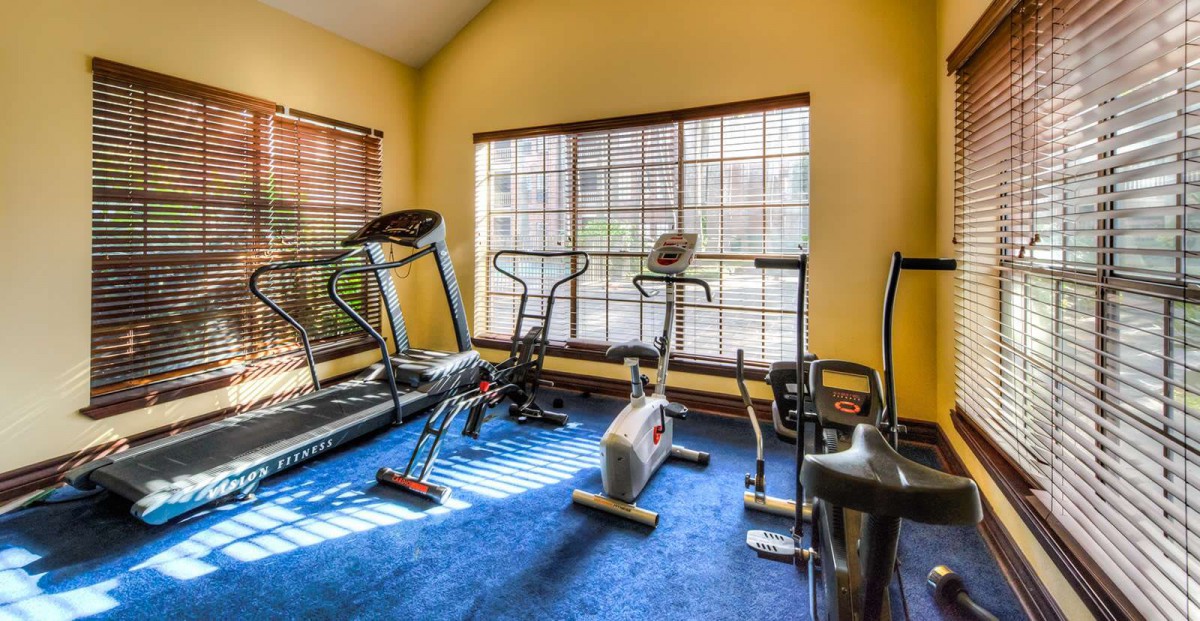 A home gym with various exercise equipment including a treadmill, stationary bike, and elliptical machine.