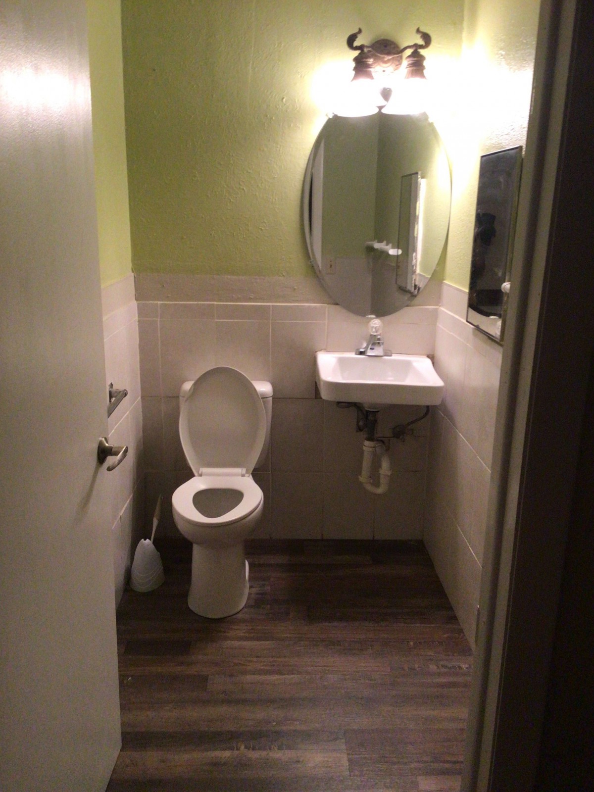 A small bathroom with a toilet, sink, and mirror.