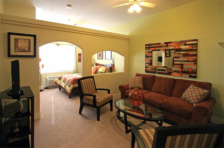 A cozy living area connected to a bedroom, featuring modern furniture and warm lighting.