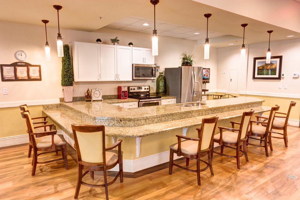 A modern kitchen with a spacious countertop, bar stools, and stainless steel appliances.