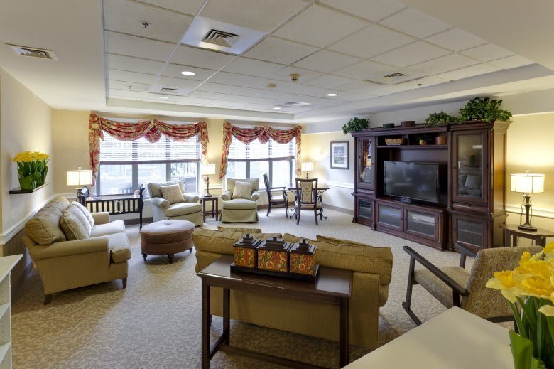 A spacious and well-lit living room with comfortable seating, a large television, and elegant decor.