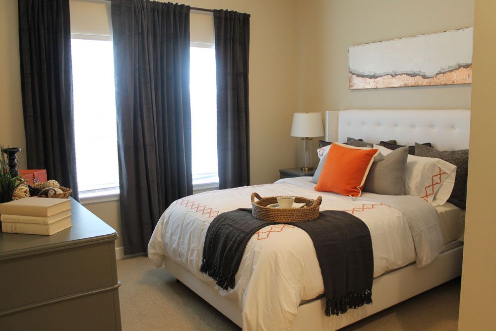 A modern and cozy bedroom with a neatly made bed, dark curtains, and stylish decor.