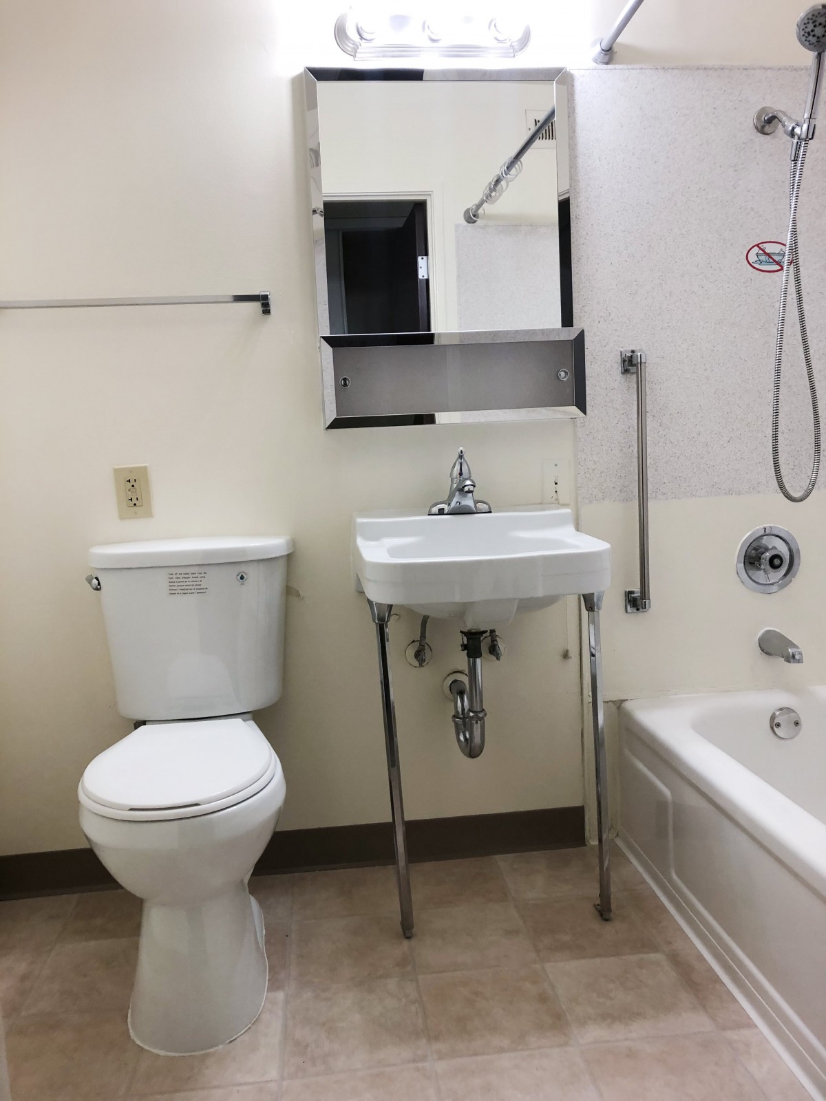 An accessible bathroom with a toilet, sink, bathtub, and grab bar.
