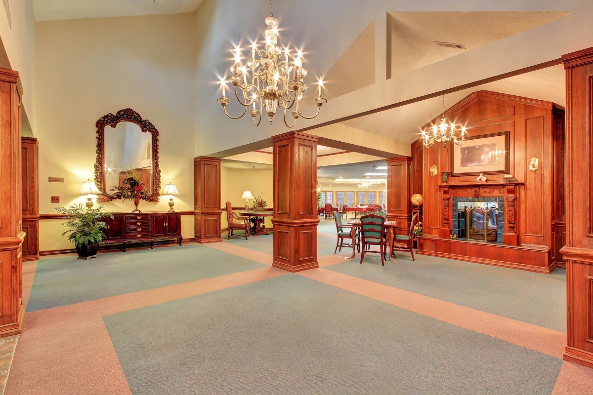 Spacious lobby area with elegant chandelier and classic wood paneling.