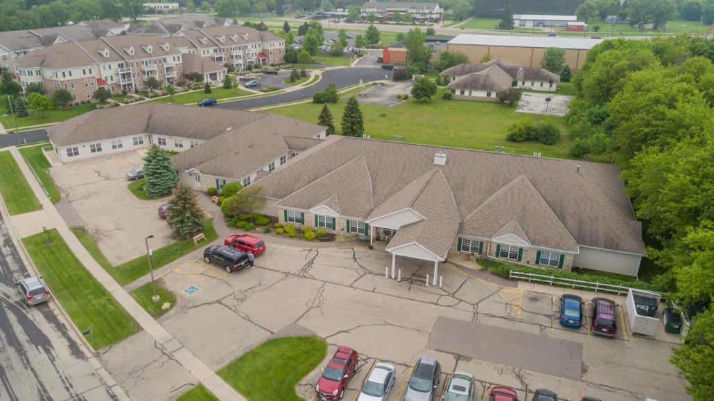Aerial view of a suburban residential building with a parking lot and surrounding greenery.