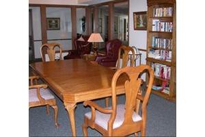 A cozy library room with a wooden table, chairs, and bookshelves.