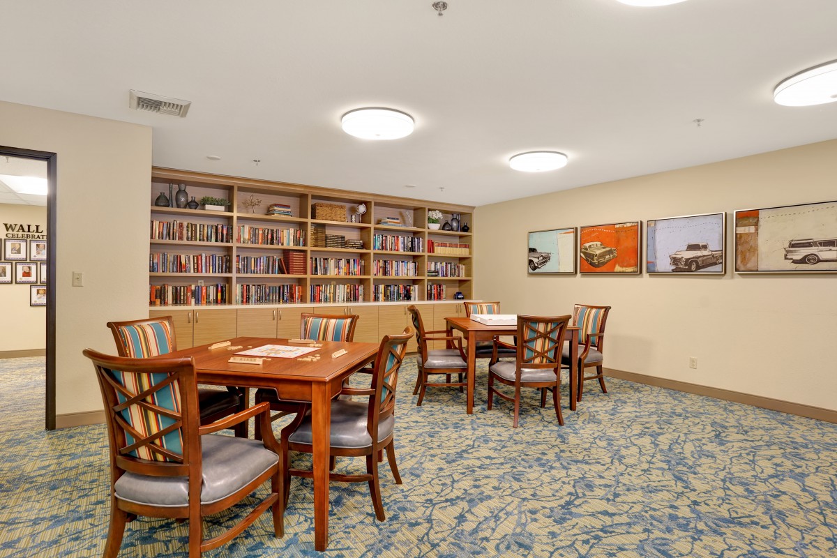 A cozy library room with bookshelves, tables, and chairs for reading.