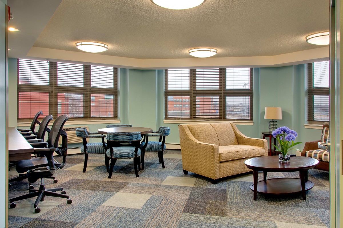 A modern office lounge area with comfortable seating and large windows.