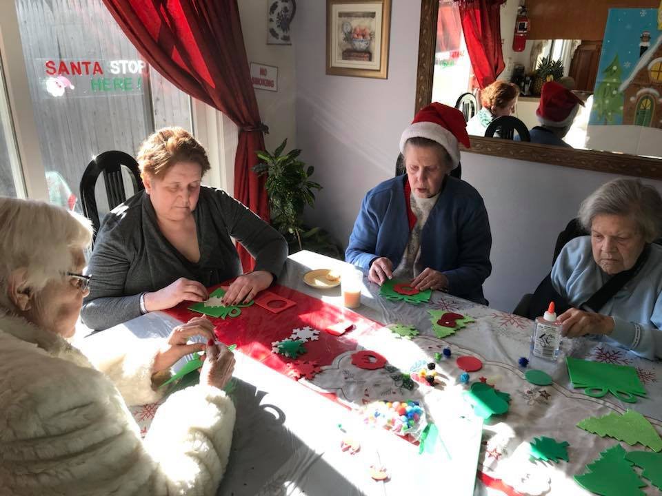 A group of people engaged in holiday crafting around a table decorated for Christmas.