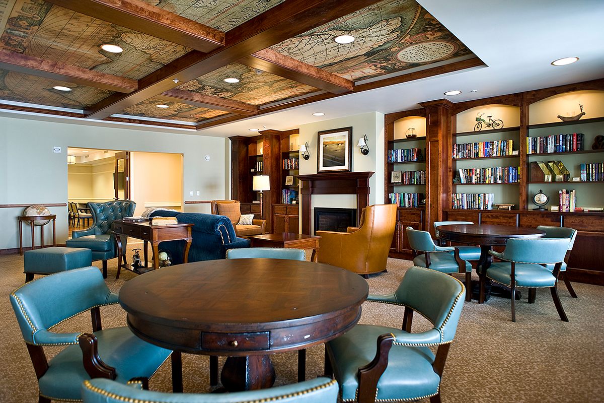 A cozy library interior with wooden furniture, bookshelves, and a fireplace.