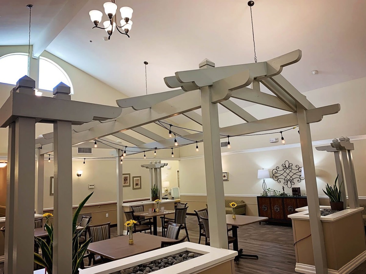 A well-lit indoor dining area with chandeliers, tables, and decorative elements.