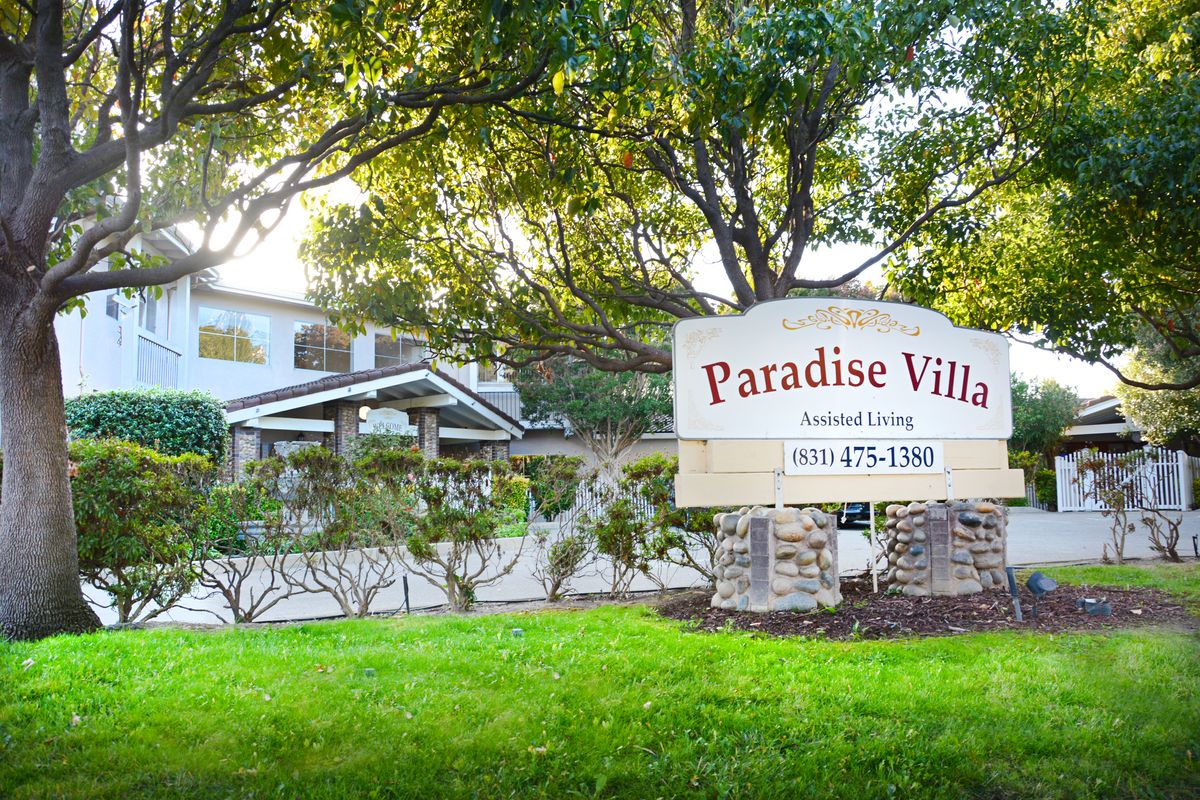 Paradise Villa assisted living facility with a landscaped garden and a welcoming sign.