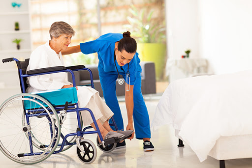 A healthcare professional assists an elderly patient in a wheelchair, demonstrating the importance of compassionate care.