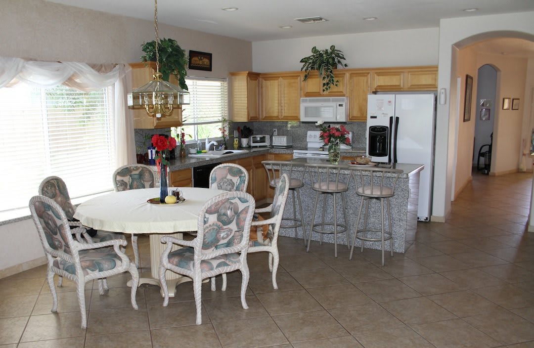 A cozy kitchen and dining area featuring a round table with chairs, barstools at the counter, and various kitchen appliances.