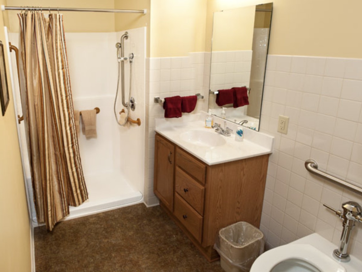 A clean and organized bathroom with a shower, sink, mirror, and toilet.