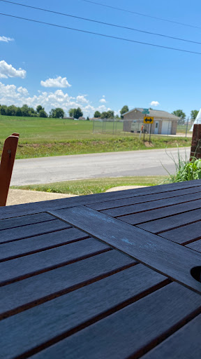 A peaceful outdoor setting featuring a wooden table, with a rural landscape and blue sky in the background.