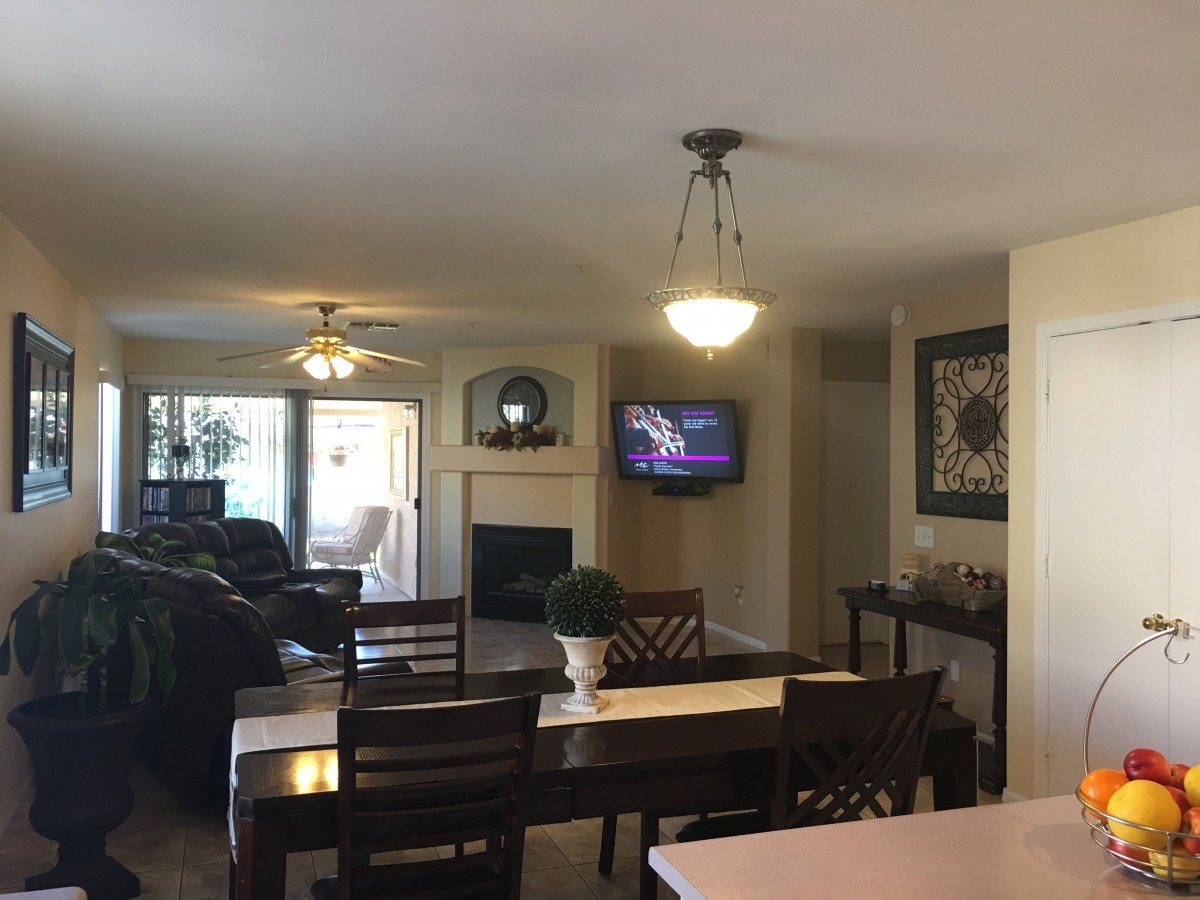 A cozy living and dining area featuring a TV mounted above a fireplace.