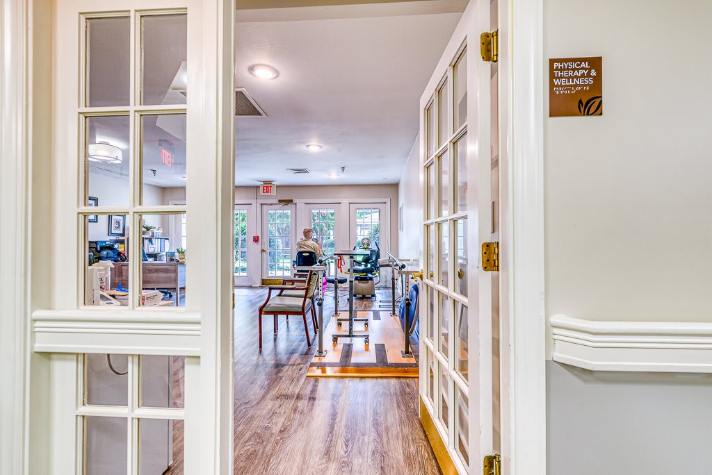 A bright and open meeting space with tables and chairs visible through a glass-paned doorway.