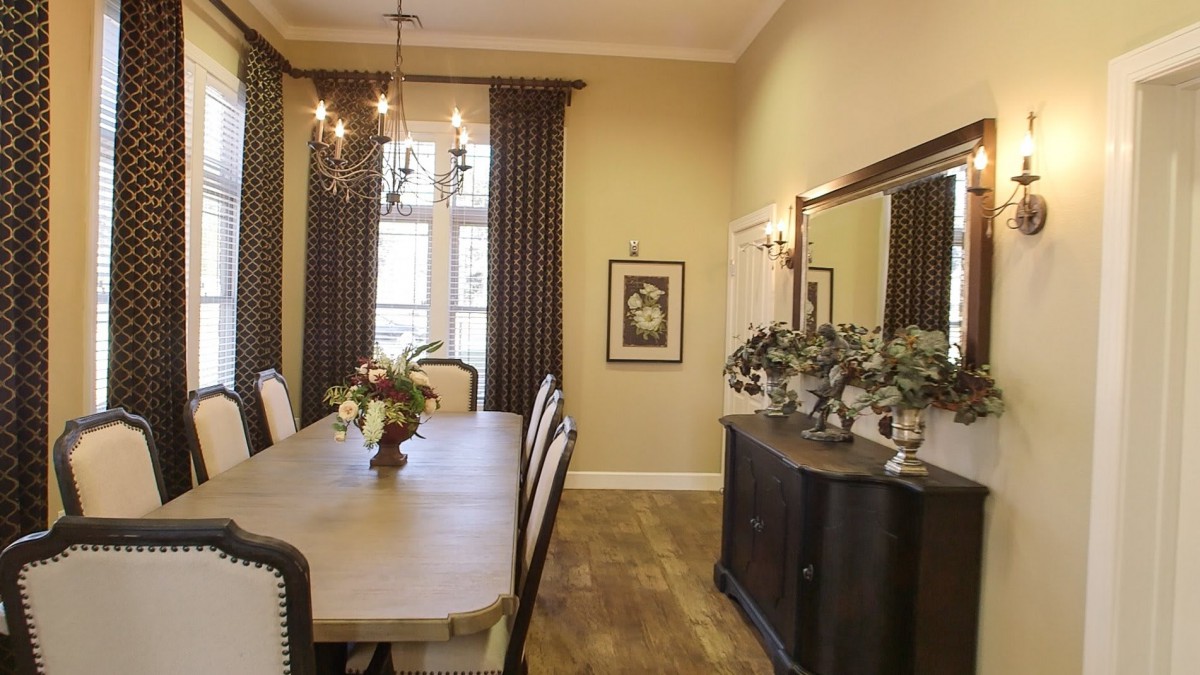 A well-decorated dining room with a long table, elegant chairs, a chandelier, and tasteful decor.
