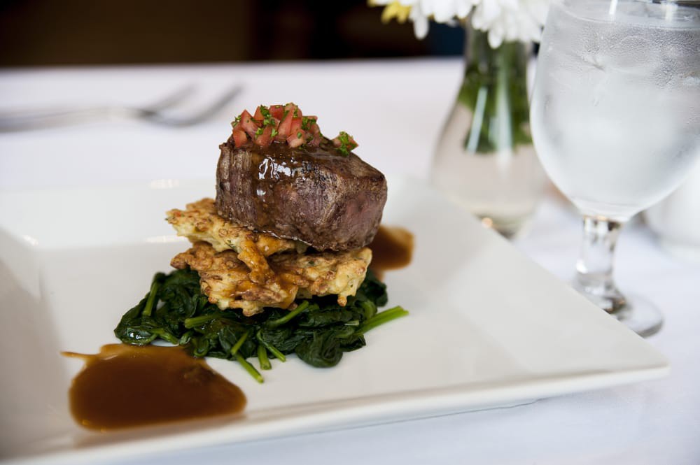 A gourmet steak dish elegantly plated with spinach and sauces.