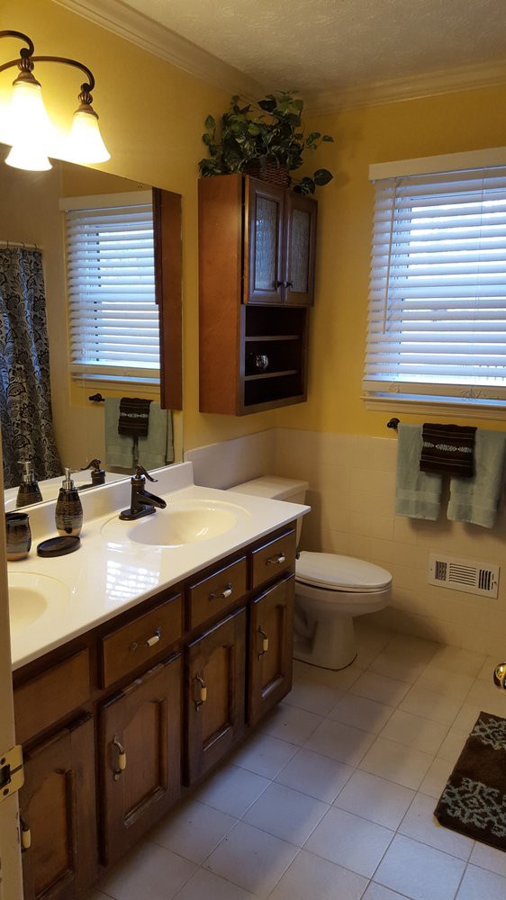 A tidy bathroom featuring wooden cabinets, a double sink with mirrors, and neatly arranged towels.