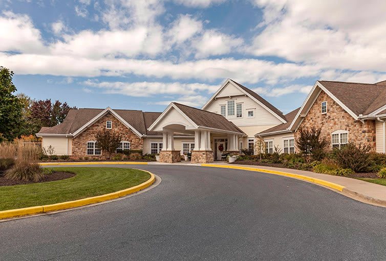 A large residential building with a circular driveway and a cloudy sky in the background.