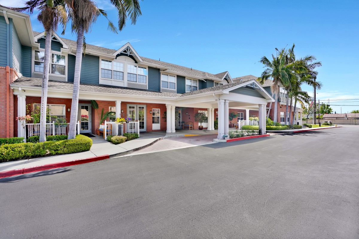 A residential building with an inviting entrance, surrounded by palm trees and a driveway.