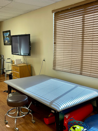 A clean and organized treatment room in a healthcare facility, equipped with a patient bed and a television monitor.