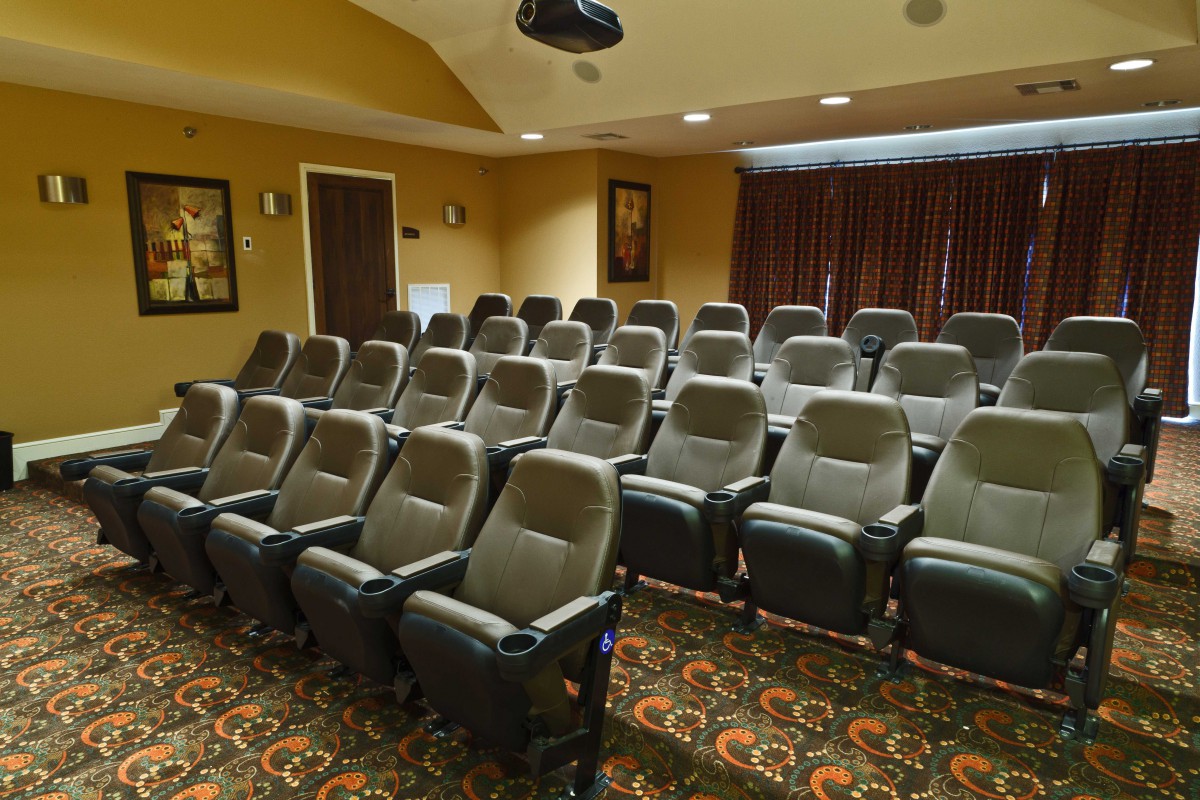 A home theater setup with multiple rows of comfortable seating and a projector.