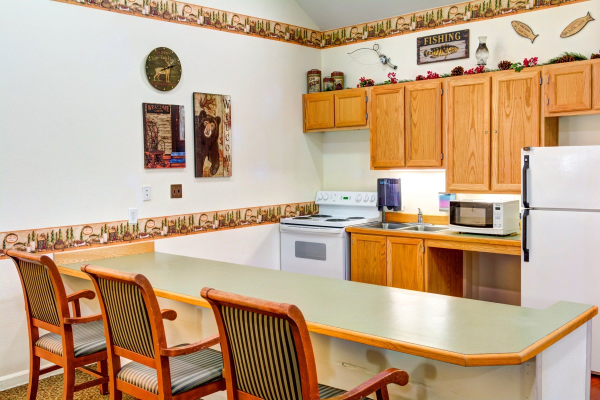 A cozy kitchen with wooden cabinets and a counter with chairs.