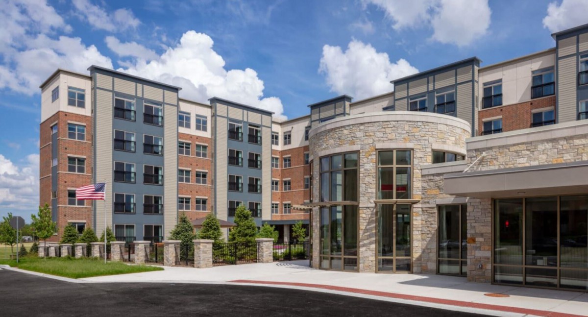 A modern residential building with a combination of brick and stone facades under a blue sky.
