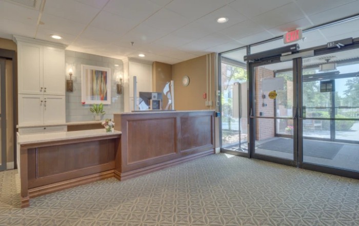 A welcoming office lobby with a reception desk and glass entrance doors.