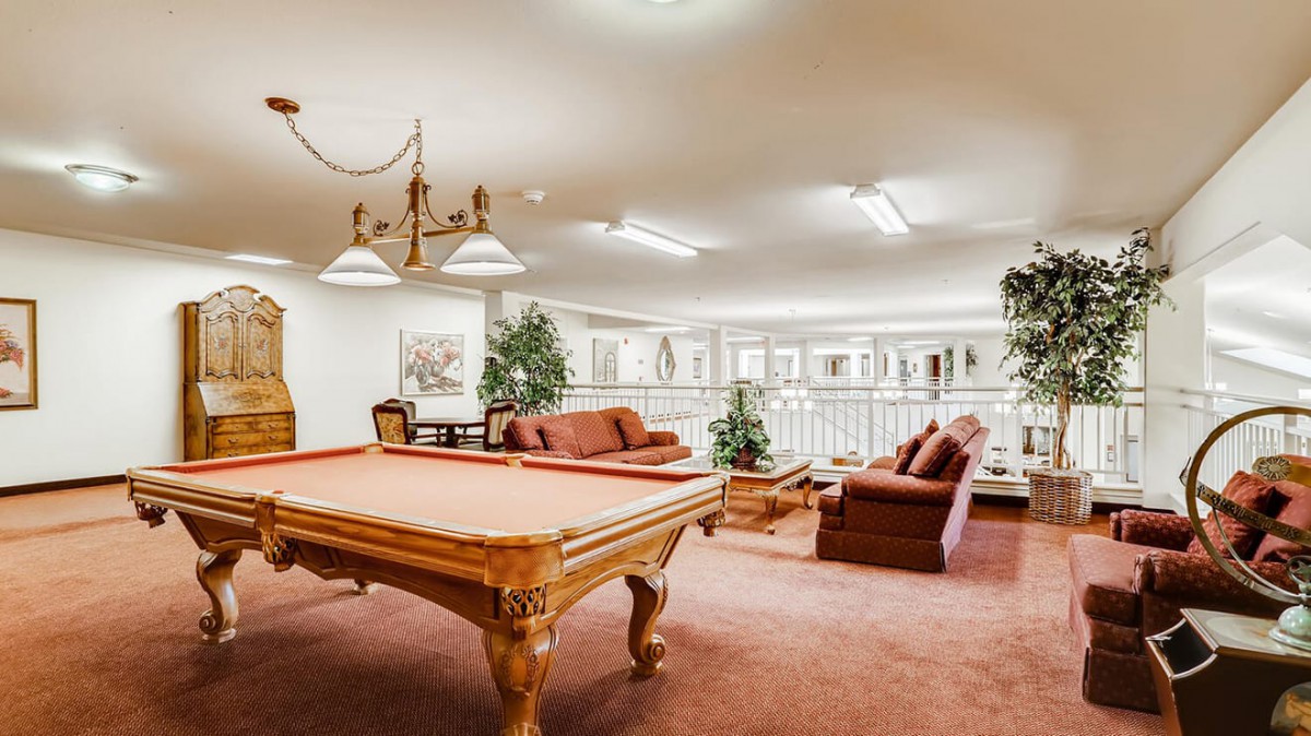 A spacious game room featuring a billiards table and comfortable seating.