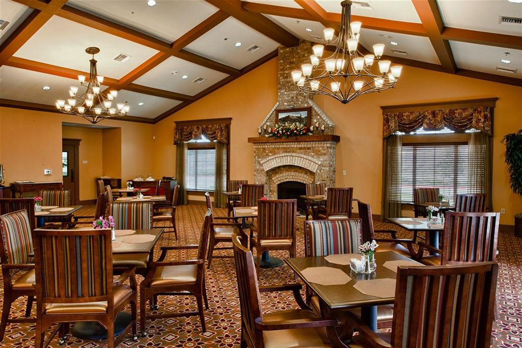 Elegant dining room with a rustic fireplace and classic chandeliers.