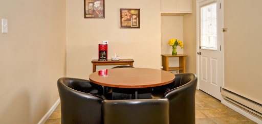 A cozy dining area featuring a round table surrounded by black chairs, with decorative artwork on the walls and a small vase of flowers.