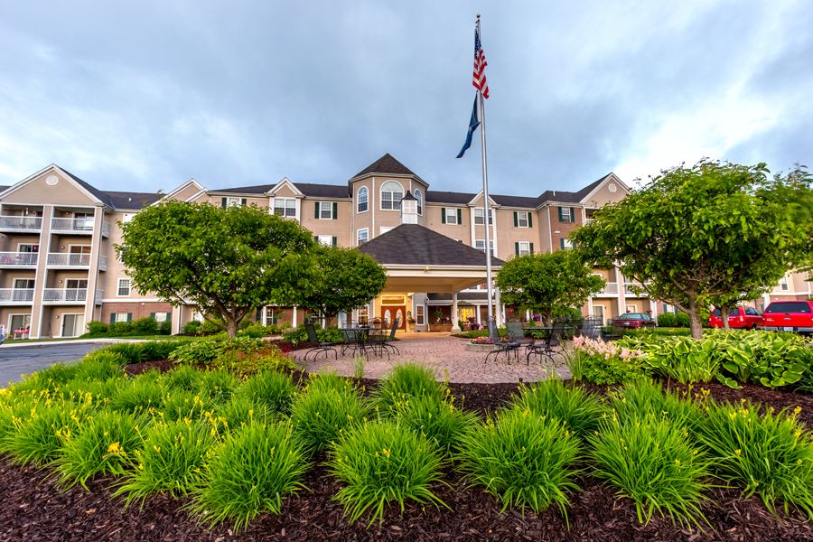 A view of a hotel entrance with landscaped gardens and an American flag in the foreground.